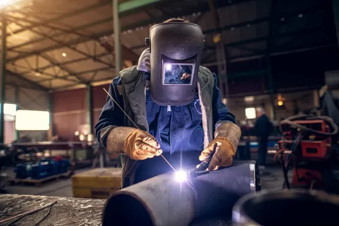 Close Up Portrait View Professional Mask Protected Welder Man Uniform Working Metal Sculpture Table Industrial Fabric Workshop Front Few Other Workers X - Certified Welder study guide