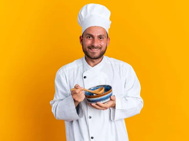 Smiling Young Caucasian Male Cook Chef Uniform Cap Holding Spoon Bowl Looking Camera Isolated Orange Wall X - Certified Sous Chef study guide