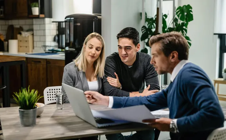 Young Couple Real Estate Agent Using Laptop While Going Through Housing Plan Meeting - Certified Secure and Fair Enforcement Mortgage Loan Originator study guide